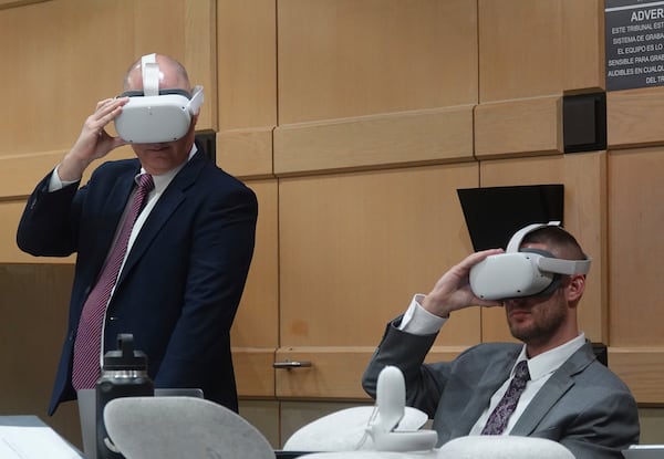 Defense attorneys Ken and Jason Padowitz watch a virtual reality presentation, Thursday, Dec. 17, 2024, at the Broward County Courthouse in Fort Lauderdale during a hearing on the admissibility of a virtual reality depiction in a stand-your-ground case. Miguel Rodriguez Albisu, 59, owner of a wedding venue in Southwest Ranches, is accused of pulling a gun on wedding guests who did not leave after he said they were supposed to. (Joe Cavaretta/South Florida Sun Sentinel via AP)