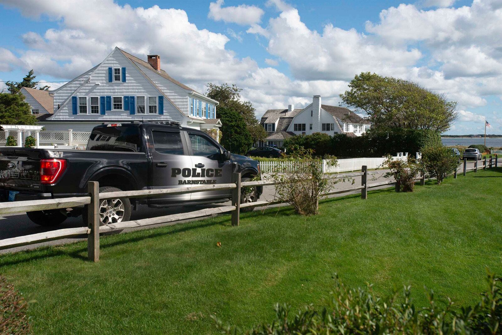 A Barnstable Police truck is stationed at the entrance to Marchant Ave. at the entrance to the Kennedy compound, Thursday, Oct. 10, 2024, in Hyannis, Mass., to provide security following the announcement of the death of Ethel Kennedy, whose home is at background right. (Steve Heaslip/Cape Cod Times via AP)