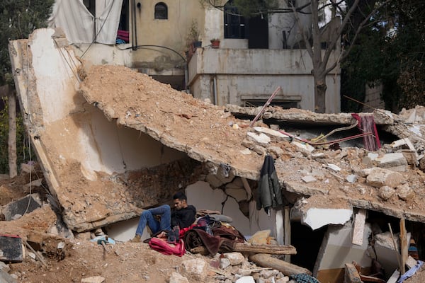 A man sits on the rubble of a destroyed house in Baalbek, eastern Lebanon, Thursday, Nov. 28, 2024. (AP Photo/Hassan Ammar)