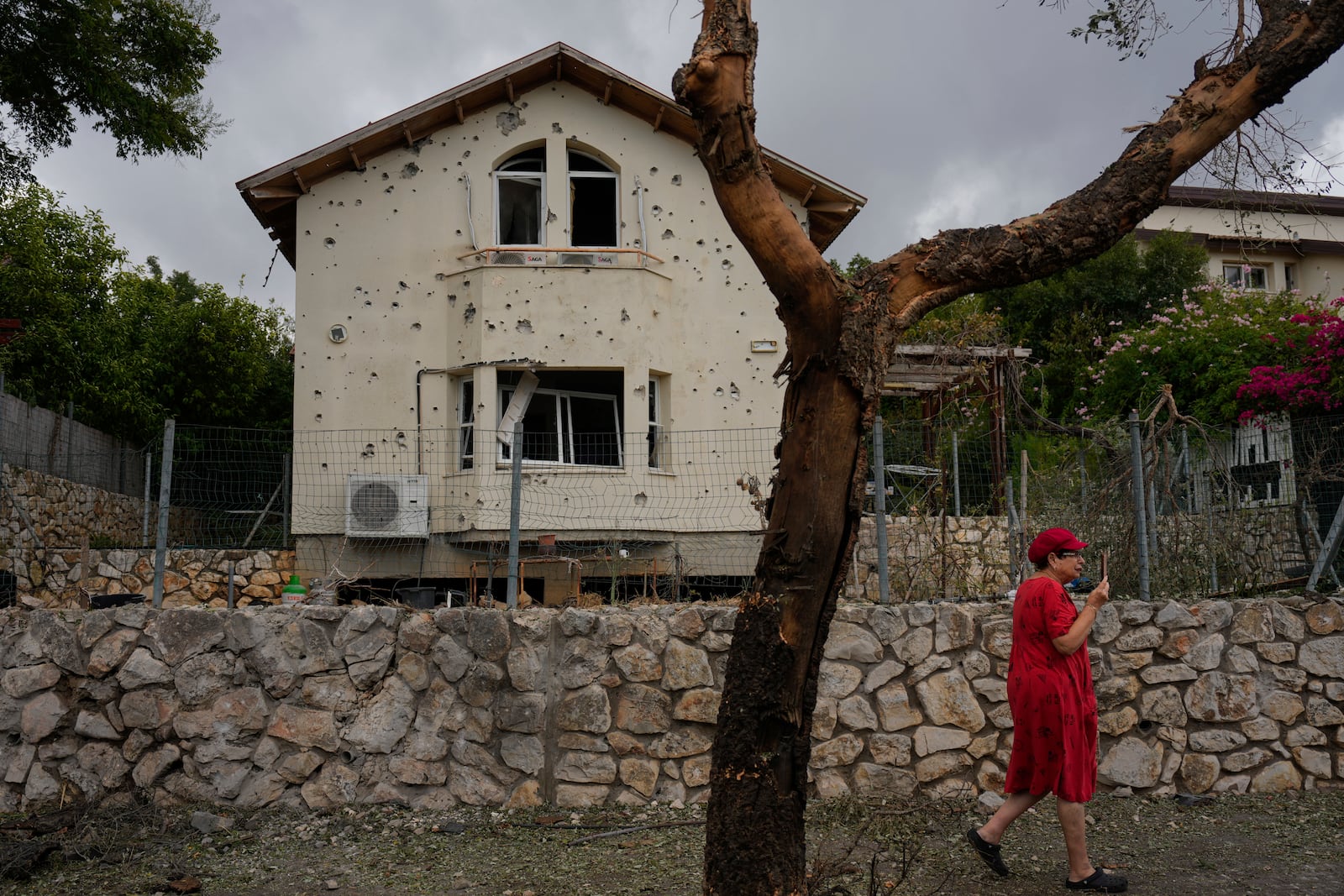 A woman walks past a house hit by a rocket fired from Lebanon, in Moreshet, northern Israel, on Sunday, Sept. 22, 2024. (AP Photo//Ariel Schalit)