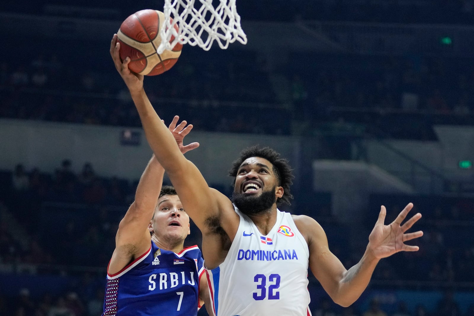 FILE - Dominican Republic forward Karl-Anthony Towns (32) against Serbia guard Bogdan Bogdanovic (7) during their Basketball World Cup second round match at the Araneta Coliseum, Manila, Philippines on Sunday Sept. 3, 2023. (AP Photo/Aaron Favila, File)