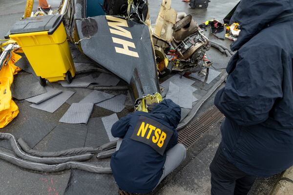 In this image released by the National Transportation Safety Board, an NTSB team surveys the wreckage, April 11, 2025, in Jersey City, N.J., recovered from the Bell 206L-4 helicopter that crashed into Hudson River on April 10, between New York City and New Jersey. (NTSB via AP)