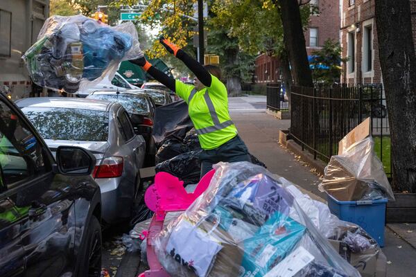 A sanitation worker throws trash to the sanitation truck, Saturday, Nov. 16, 2024, in the Brooklyn borough of New York. (AP Photo/Yuki Iwamura)