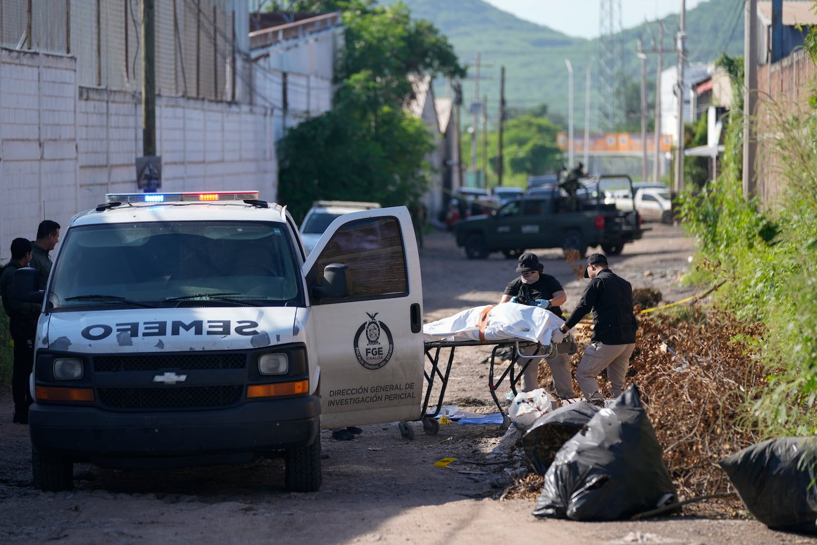 Forensic investigators remove a body from the street in La Costerita, Culiacan, Sinaloa state, Mexico, Thursday, Sept. 19, 2024. (AP Photo/Eduardo Verdugo)