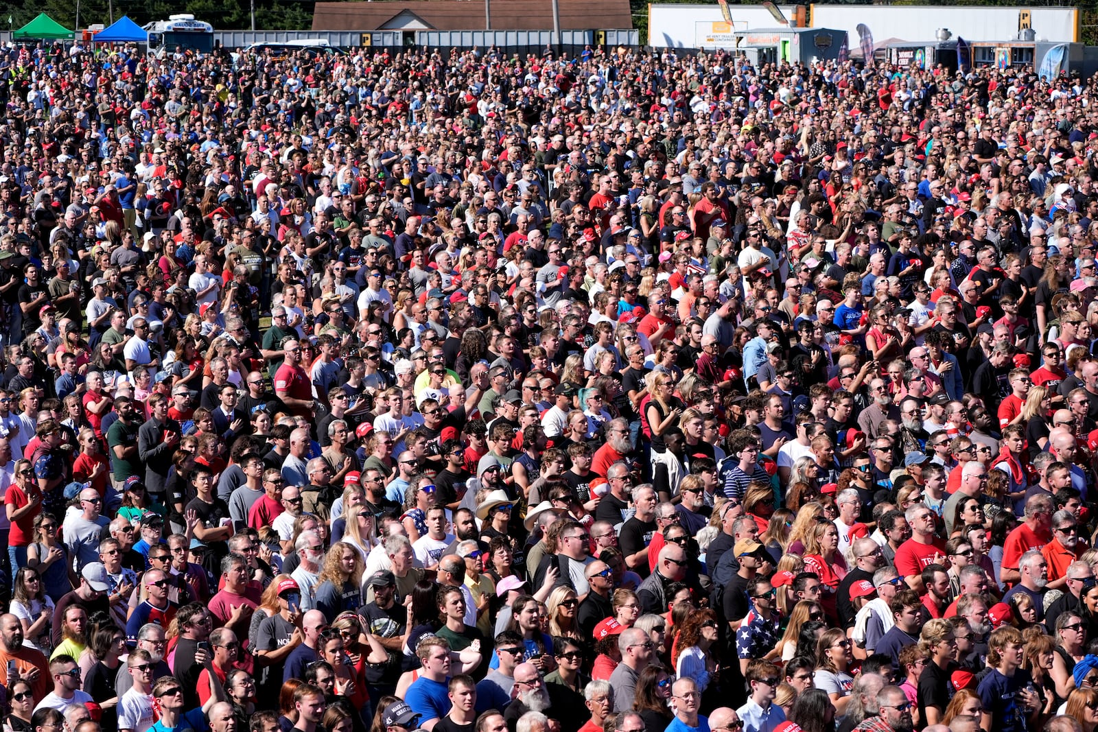 Attendees stand during the Pledge of Allegiance before Republican presidential nominee former President Donald Trump arrives to speak at a campaign event at the Butler Farm Show, Saturday, Oct. 5, 2024, in Butler, Pa. (AP Photo/Alex Brandon)