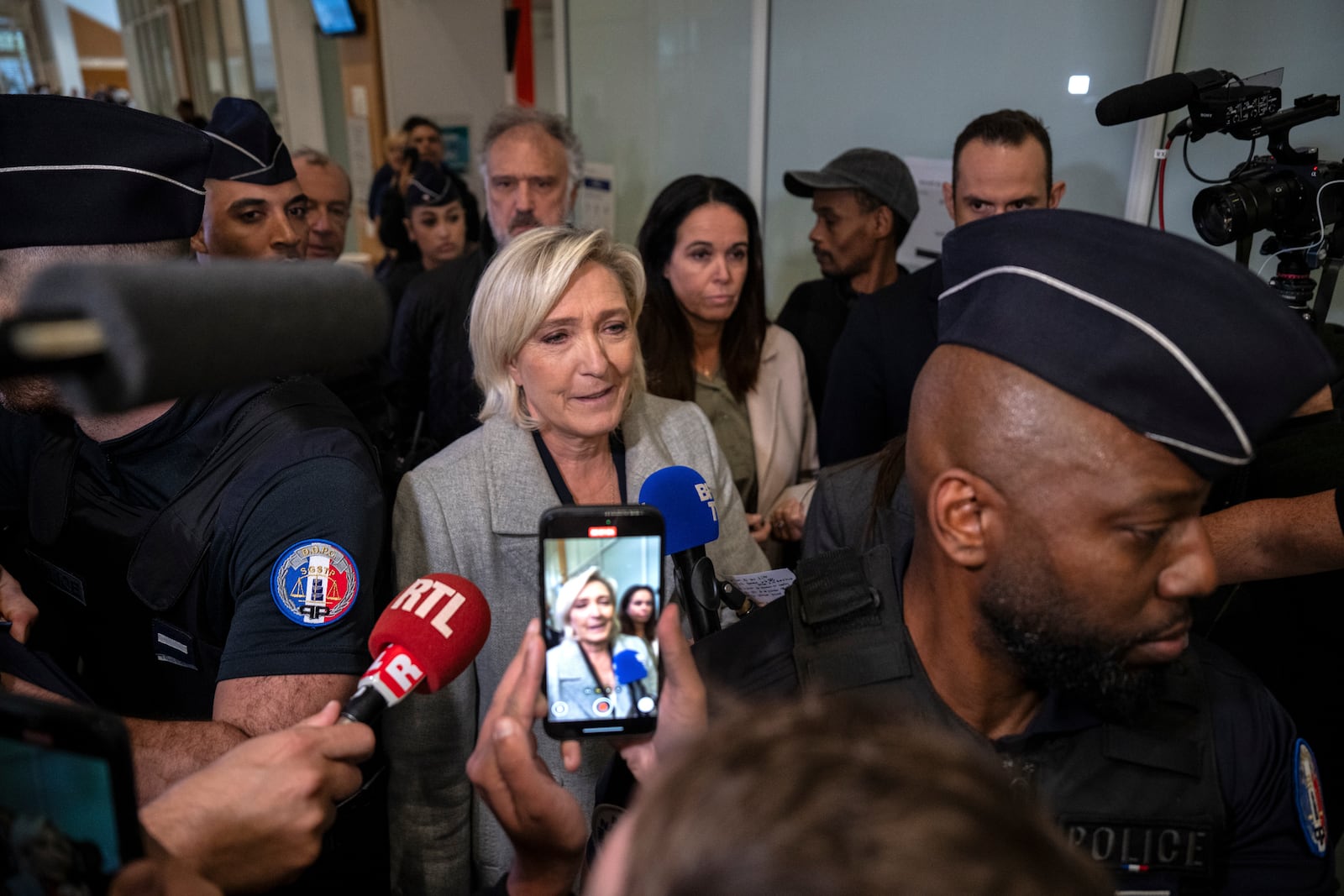 French far-right leader Marine Le Pen, front center, is flanked by police officers as she arrives at the court house in Paris, Monday, Sept. 30, 2024. (AP Photo/Louise Delmotte)