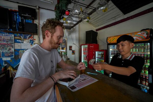 A foreign tourist buys coffee at Nana Backpack hostel bar in Vang Vieng, Laos, Tuesday, Nov. 19, 2024. (AP Photo/Anupam Nath)