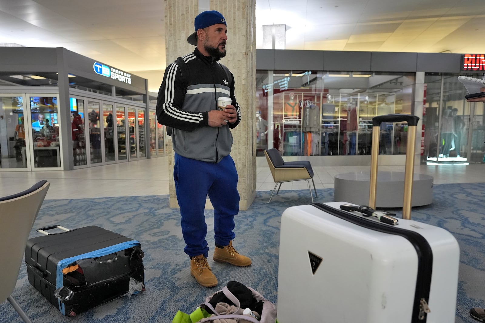 John Fedor, of New Jersey, waits for transportation help to get to a shelter after his flight was canceled Tuesday, Oct. 8, 2024, at the Tampa International Airport in Tampa, Fla., due to the possible arrival of Hurricane Milton. (AP Photo/Chris O'Meara)