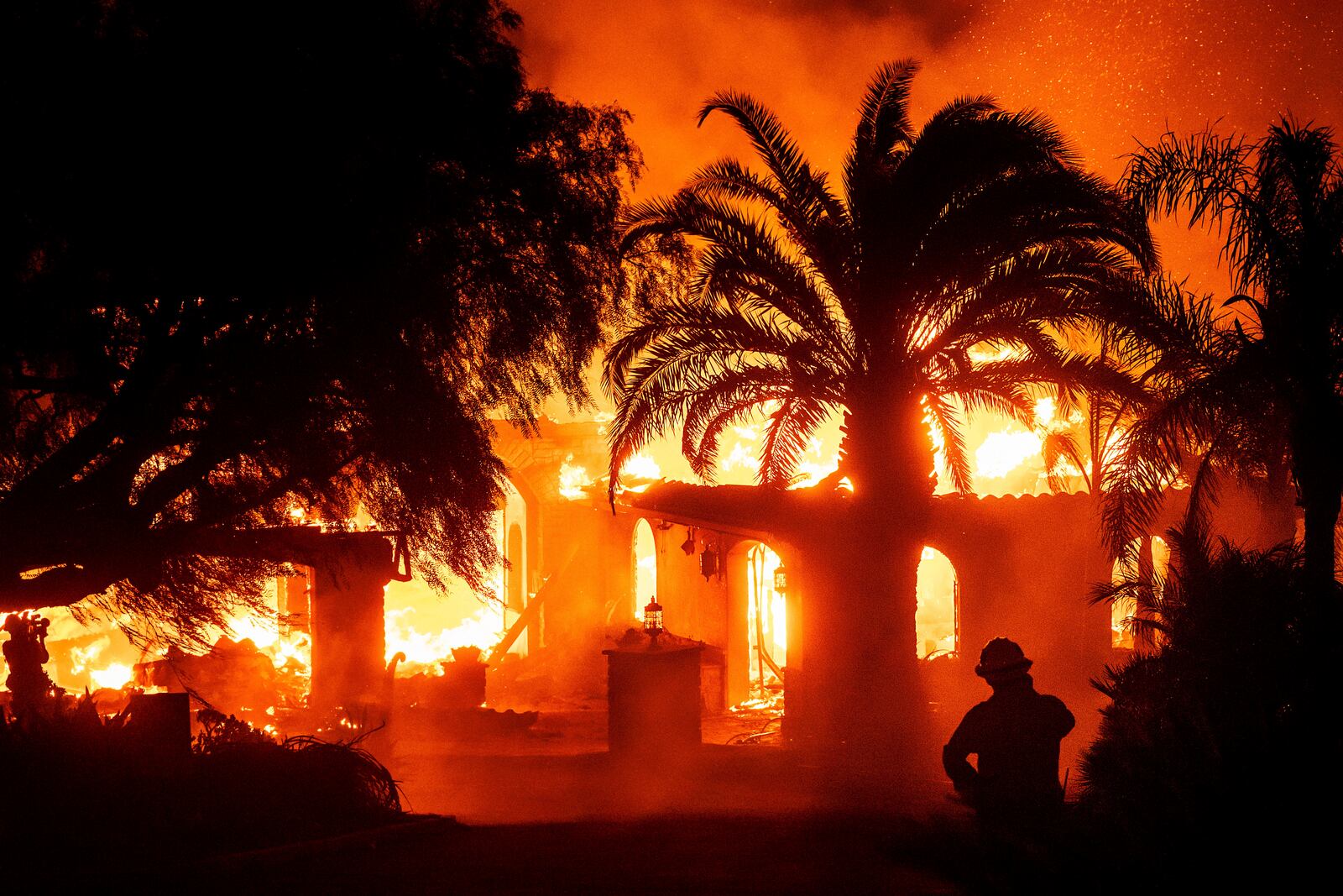 A firefighter watches as flames from the Mountain Fire consume a home in Camarillo, Calif., on Wednesday, Nov. 6, 2024. (AP Photo/Noah Berger)