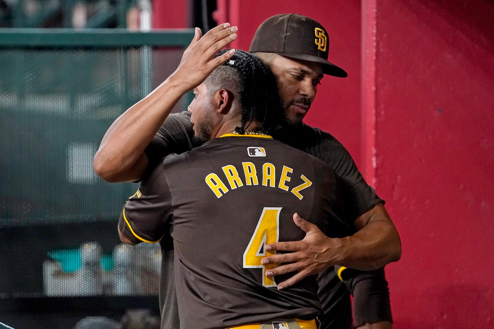 San Diego Padres' Luis Arraez (4) gets a hug in the dugout from teammate Xander Bogaerts, right, after hitting a double against the Arizona Diamondbacks during the sixth inning of a baseball game, Sunday, Sept. 29, 2024, in Phoenix. (AP Photo/Darryl Webb)