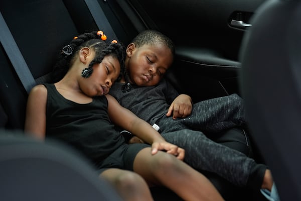 FILE - Siblings Saboria, 4, left, and Messiah Tyler, 3, nap in the backseat of a car after the roof was torn off the home where they lived with their mom, grandparents, an aunt and an uncle during the passage of Hurricane Milton, in Palmetto, Fla., Oct. 10, 2024. The family of seven rode out the storm in a government shelter, and returned home to find most of the roof gone and their furniture and belongings destroyed by rainwater. (AP Photo/Rebecca Blackwell, File)