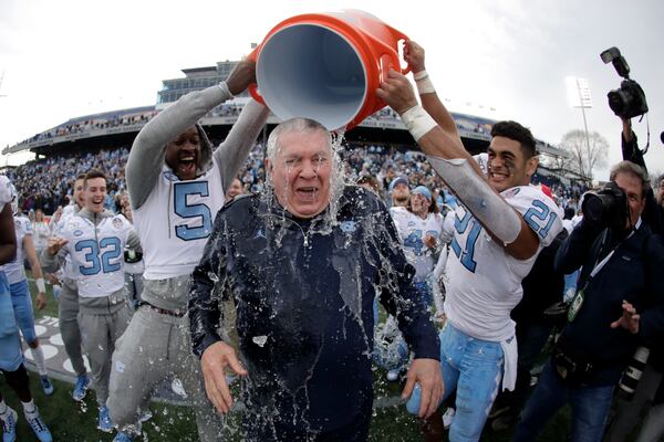 FILE - North Carolina head coach Mack Brown, center, is doused by defensive back Patrice Rene, left, and linebacker Chazz Surratt during the second half of the Military Bowl NCAA college football game against Temple, Friday, Dec. 27, 2019, in Annapolis, Md. (AP Photo/Julio Cortez, File)