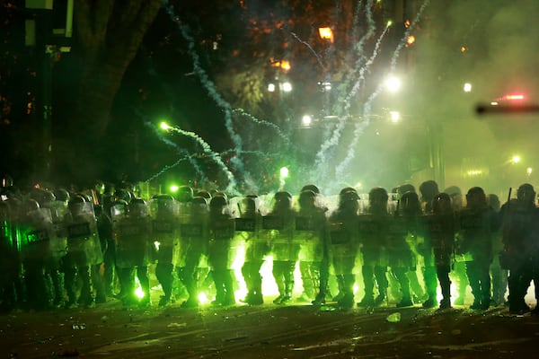 Demonstrators use firecrackers against police as police block a street to prevent protesters rallying against the government's decision to suspend negotiations on joining the European Union for four years, outside the parliament's building in Tbilisi, Georgia, early Sunday, Dec. 1, 2024. (AP Photo/Zurab Tsertsvadze)