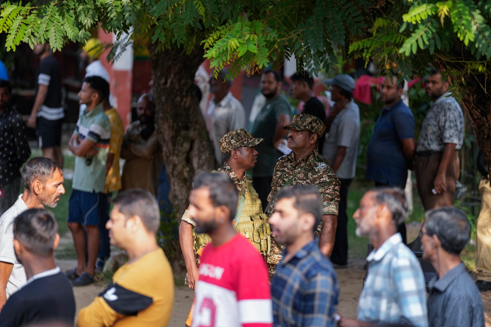 Paramilitary soldiers guard as people queue up to cast their vote at a polling booth during the final phase of an election to choose a local government in Indian-controlled Kashmir, in Jammu, India, Tuesday, Oct.1, 2024. (AP Photos/Channi Anand)