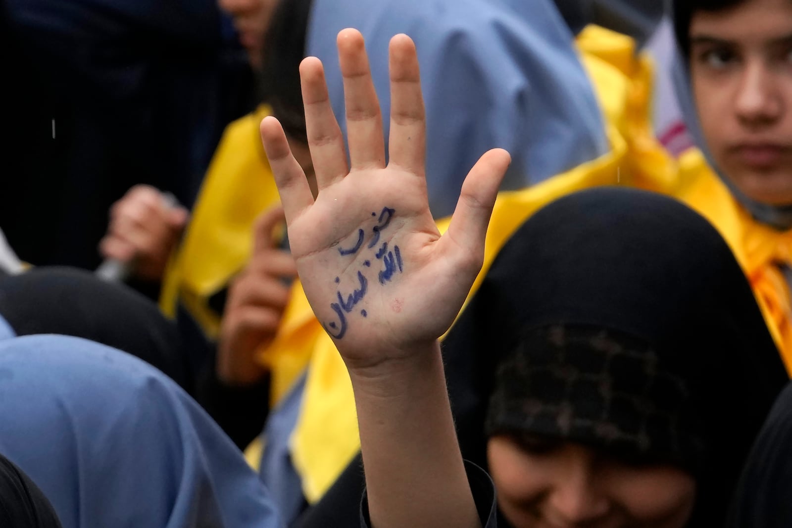 An Iranian schoolgirl holds up her hand with a sign reading in Farsi: "Lebanon's Hezbollah" in an annual rally in front of the former U.S. Embassy in Tehran, Iran, Sunday, Nov. 3, 2024, marking the 45th anniversary of Iranian students' takeover of the embassy, starting a hostage crisis. (AP Photo/Vahid Salemi)