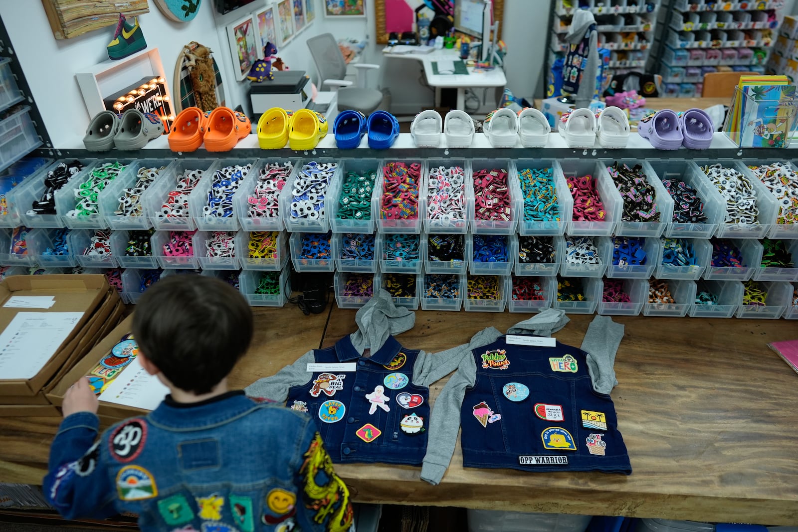 Oliver Burkhardt, 13, shows how staff lays out patches on denim jackets being prepared for kids battling cancer, inside the offices of the Oliver Patch Project, Wednesday, Sept. 4, 2024, in Miami. (AP Photo/Rebecca Blackwell)