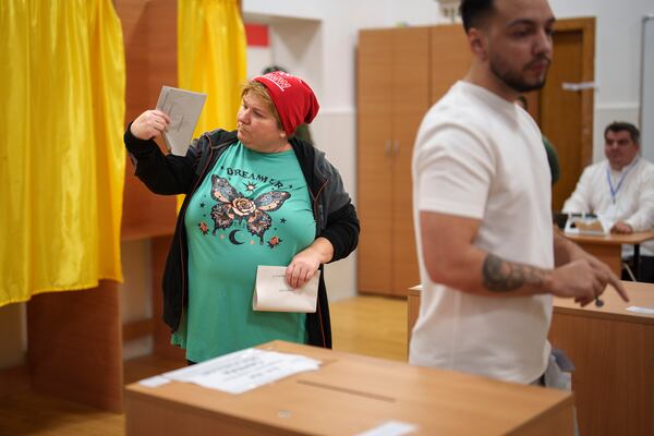 A woman holds ballot papers before casting her vote in the country's parliamentary election in Mogosoaia, Romania, Sunday, Dec. 1, 2024. (AP Photo/Vadim Ghirda)