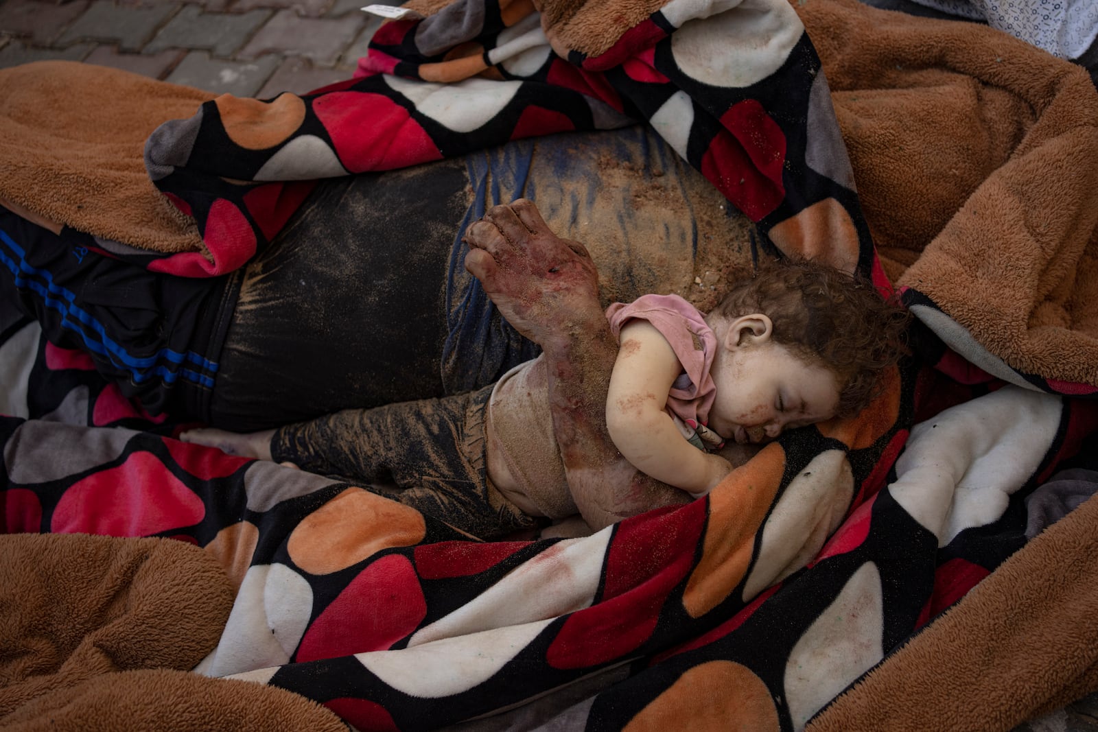 The bodies of a father and his child killed in the Israeli bombardment of the Gaza Strip, lie in front of the morgue at Al-Aqsa Hospital in Deir Al-Balah, Sunday, Oct. 22, 2023. (AP Photo/Fatima Shbair)