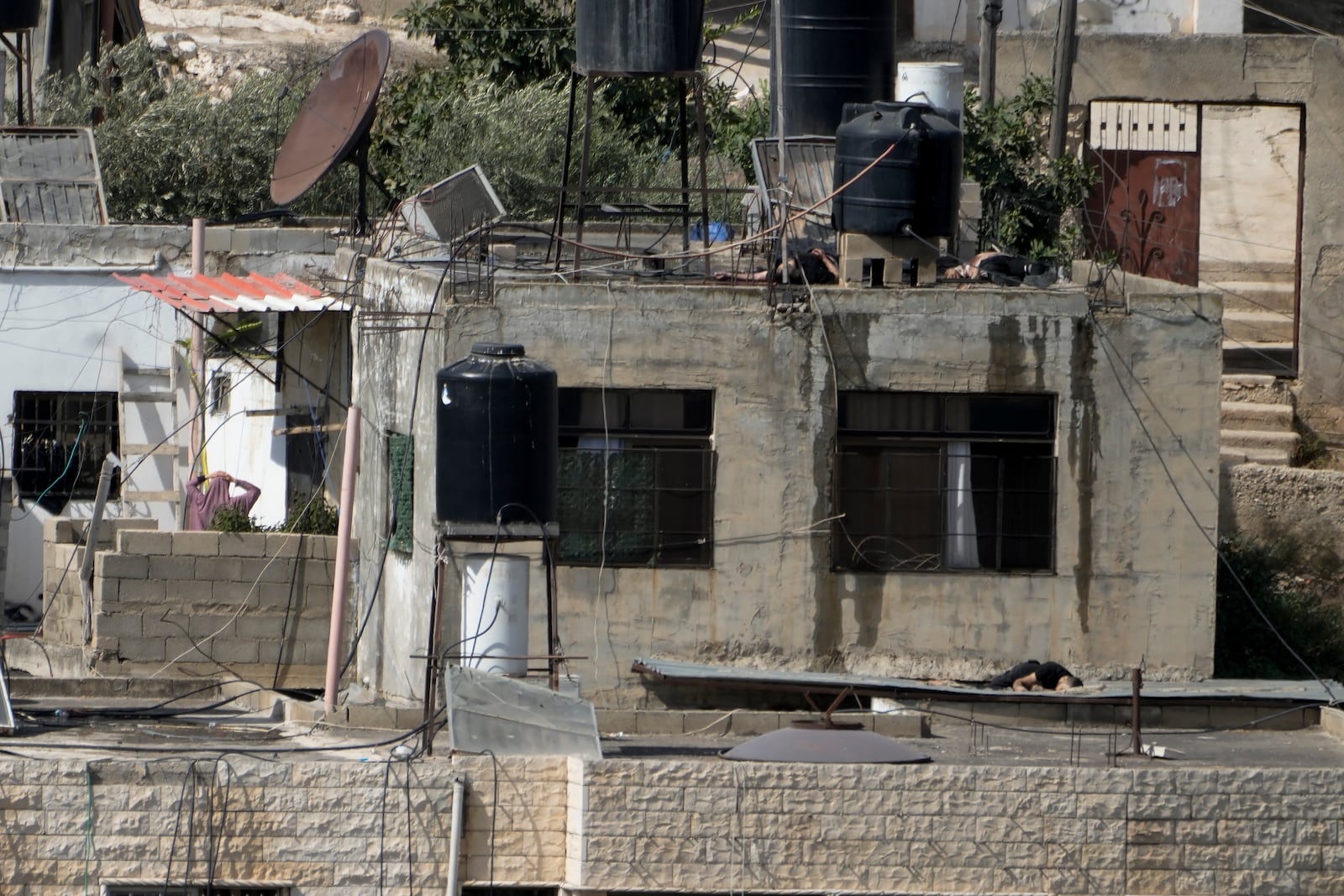 EDS NOTE: GRAPHIC CONTENT - Three bodies lie motionless on rooftops in the West Bank town of Qatabiya during a Israeli raid, Thursday, Sept. 19, 2024. (AP Photo/Majdi Mohammed)