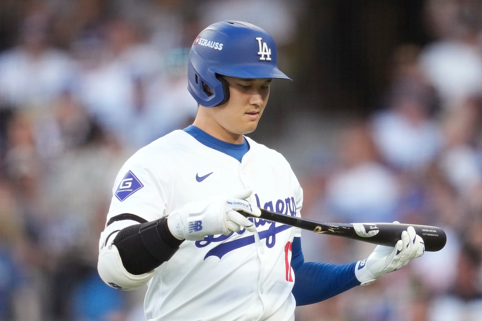 Los Angeles Dodgers' Shohei Ohtani walks back to replace his bat after breaking it on a foul ball during the third inning in Game 2 of a baseball NL Division Series against the San Diego Padres, Sunday, Oct. 6, 2024, in Los Angeles. (AP Photo/Ashley Landis)