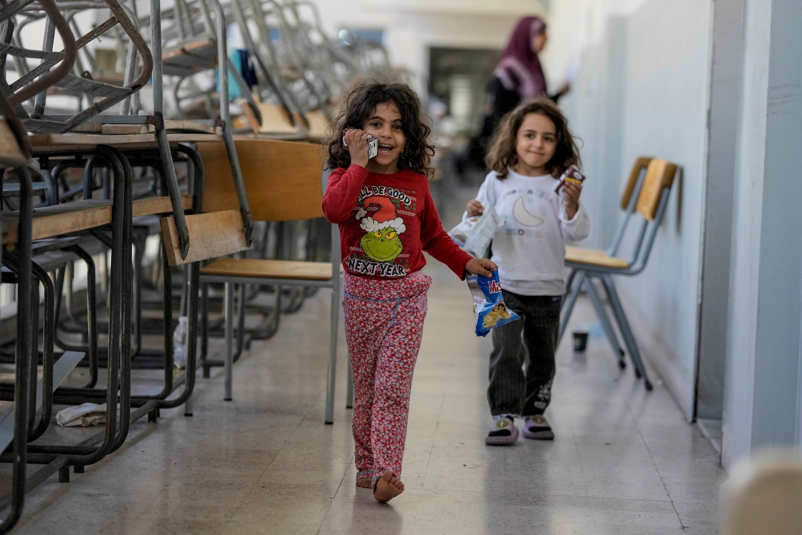 Displaced children play in a classroom at a school, in Beirut, after fleeing the Israeli airstrikes in the south with their families, Thursday, Sept. 26, 2024. (AP Photo/Bilal Hussein)