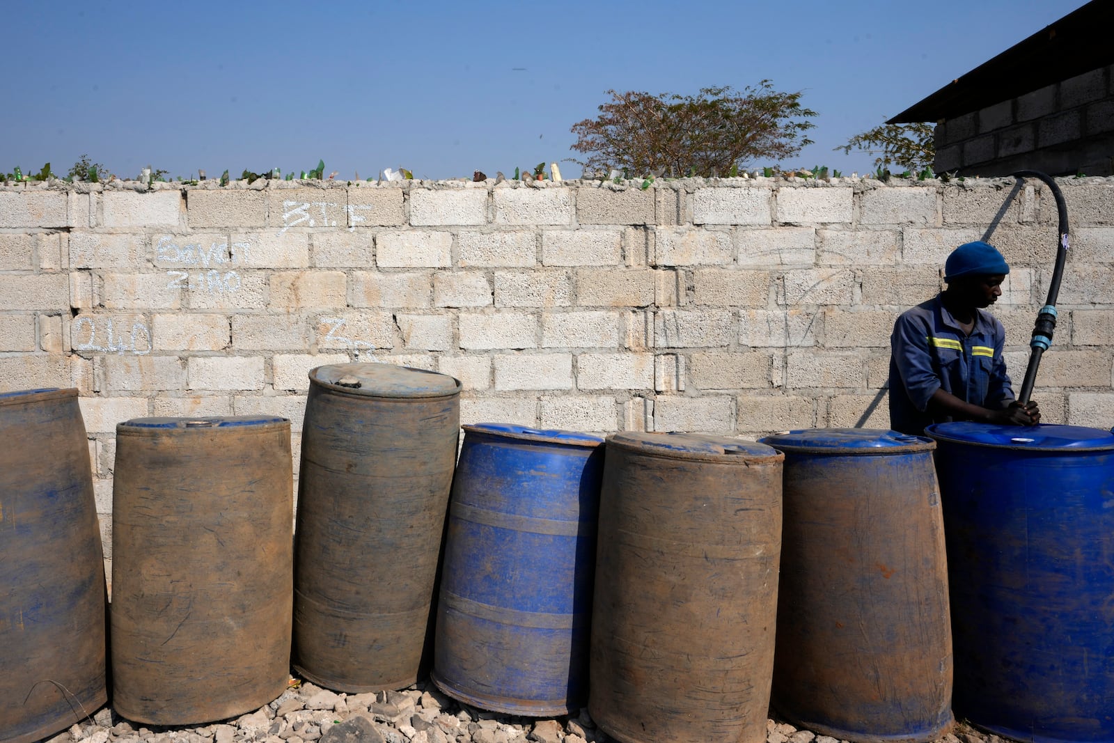 A worker fills drums with water at a collection point at Bauleni Township in Lusaka, Zambia, Tuesday, Sept. 17, 2024. (AP Photo/Themba Hadebe)