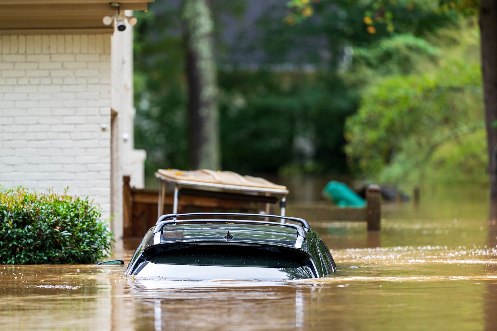 A vehicle is submerged outside a home near Peachtree Creek in Atlanta Friday, Sept. 27, 2024. (AP Photo/Jason Allen)