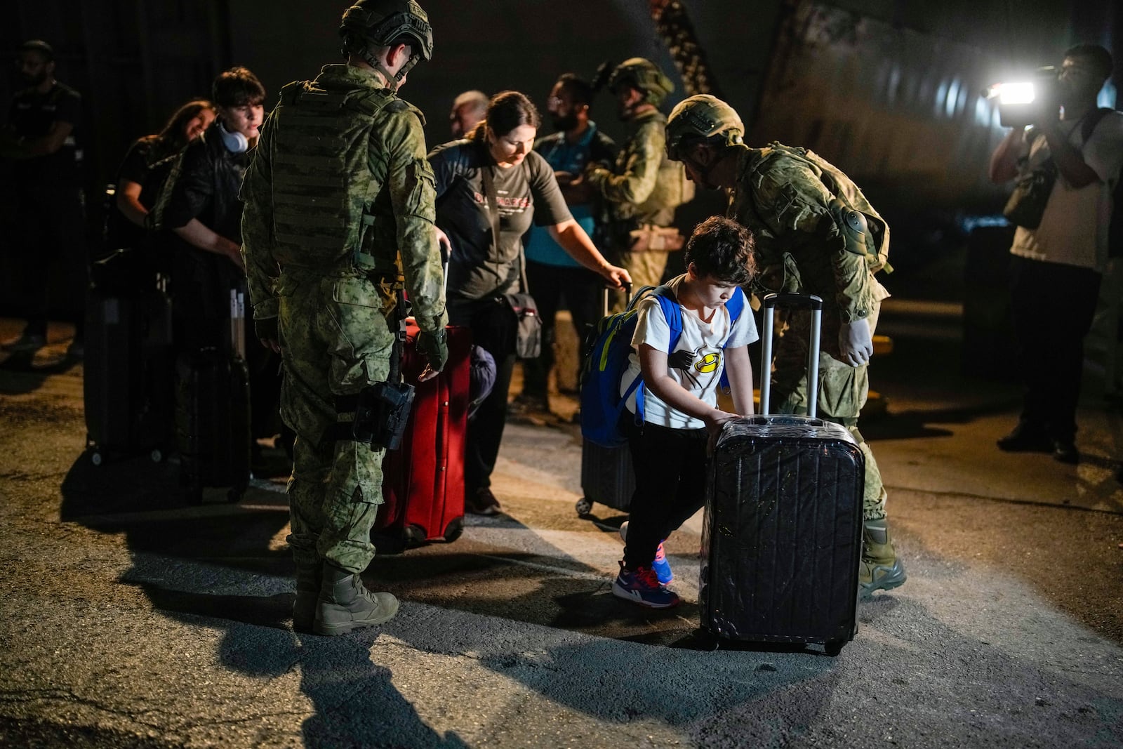 Turkish citizens walk to board Turkish military ships to evacuate them from Lebanon to Turkey, in Beirut port on Wednesday, Oct. 9, 2024. (AP Photo/Emrah Gurel)