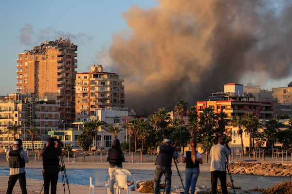 Journalists film as smoke rises from a building hit in Israeli airstrikes in Tyre, southern Lebanon, Saturday, Nov. 16, 2024. (AP Photo/Mohammed Zaatari)