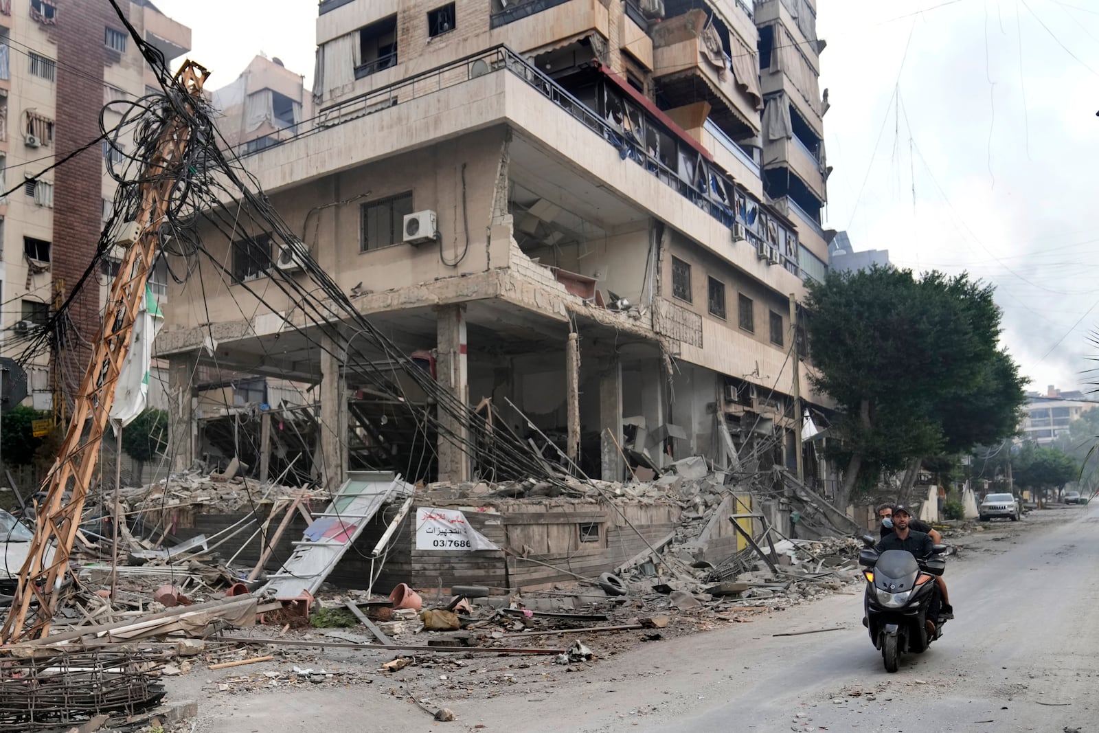 Lebanese men ride a scooter past a damaged building hit by an Israeli airstrike in Dahiyeh, Beirut, Lebanon, Monday, Oct. 7, 2024. (AP Photo/Hussein Malla)