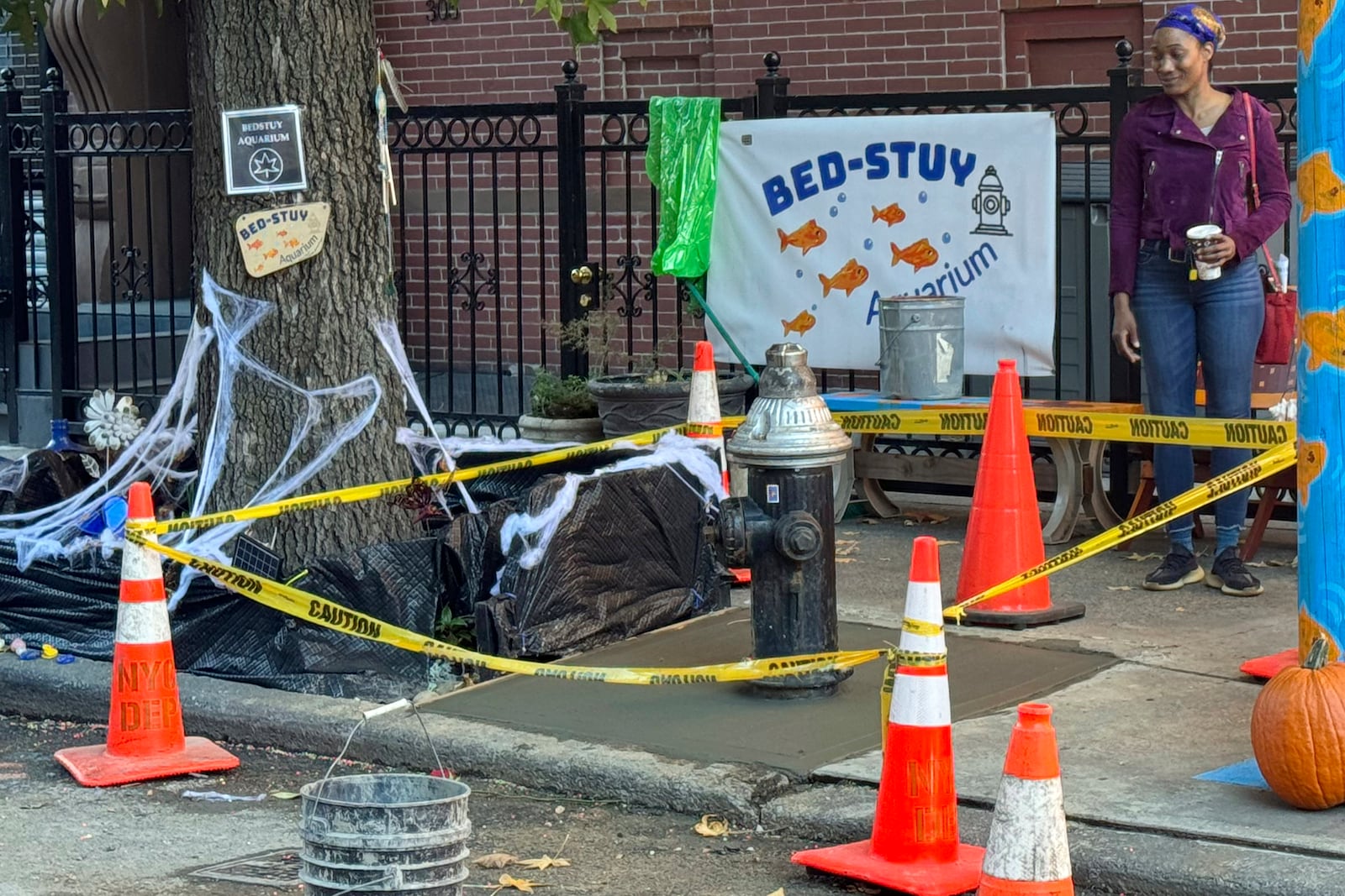 Yellow caution tape surrounds the area around a once leaky fire hydrant, that became a makeshift aquarium goldfish pool, and now has been filled with concrete by the city, Friday, Oct. 25, 2024, in the Brooklyn borough of New York. (AP Photo/Cedar Attanasio)