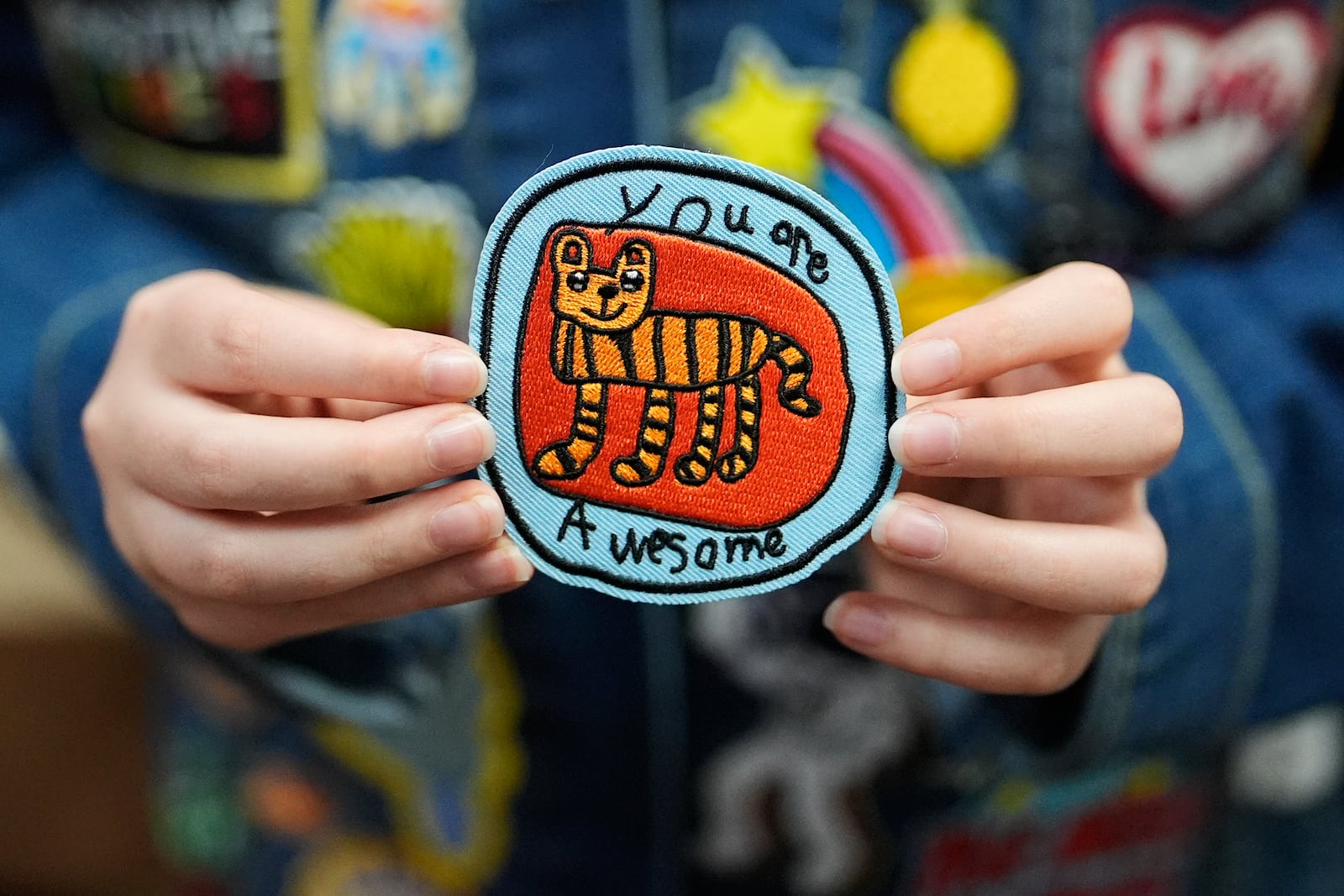 Oliver Burkhardt, 13, holds up a popular patch he designed himself, inside the offices of the Oliver Patch Project, Wednesday, Sept. 4, 2024, in Miami. (AP Photo/Rebecca Blackwell)