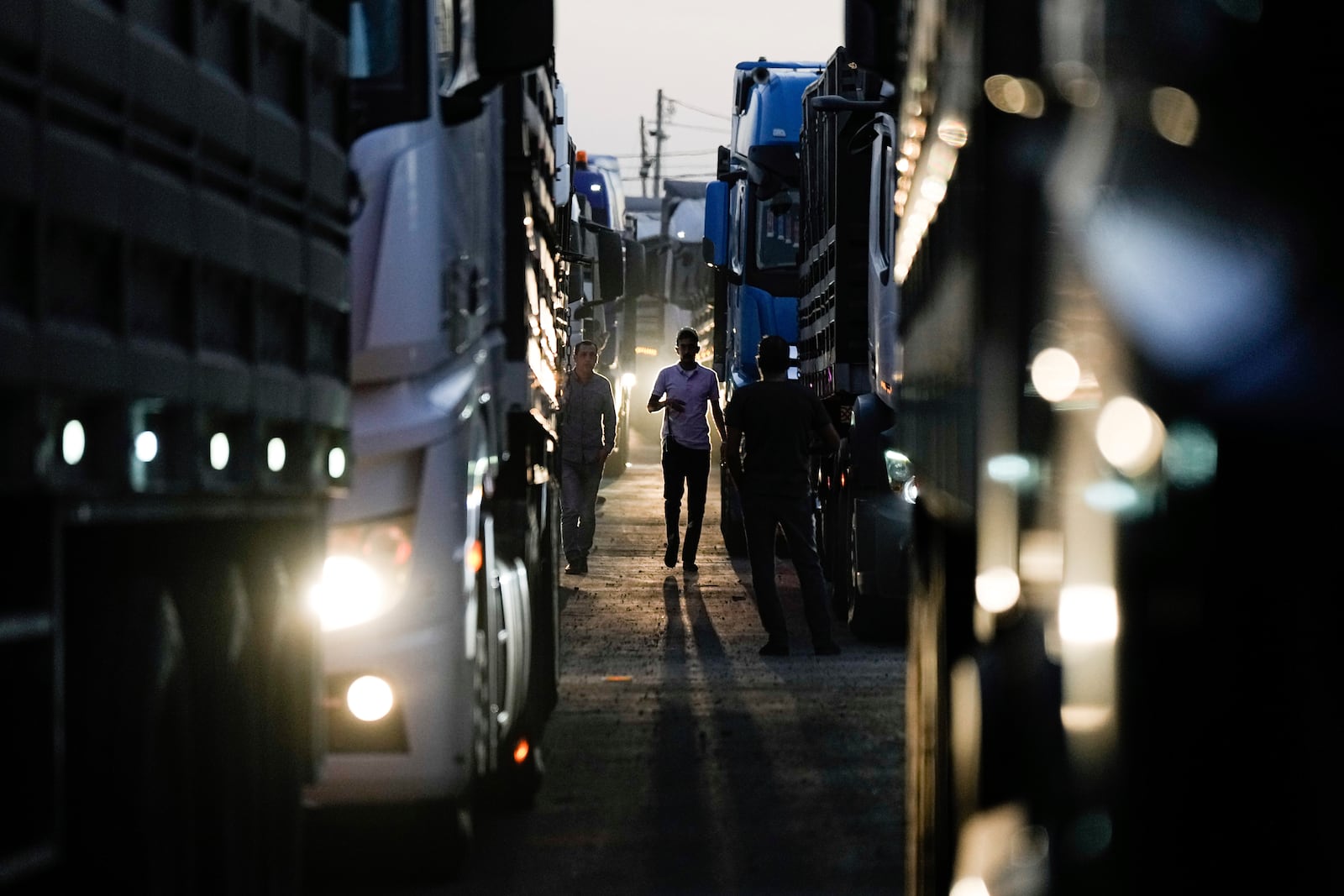 A truck driver walks between trucks carrying humanitarian aid just before they cross into the Gaza Strip at Erez crossing in southern Israel, Monday, Oct. 21, 2024. (AP Photo/Tsafrir Abayov)