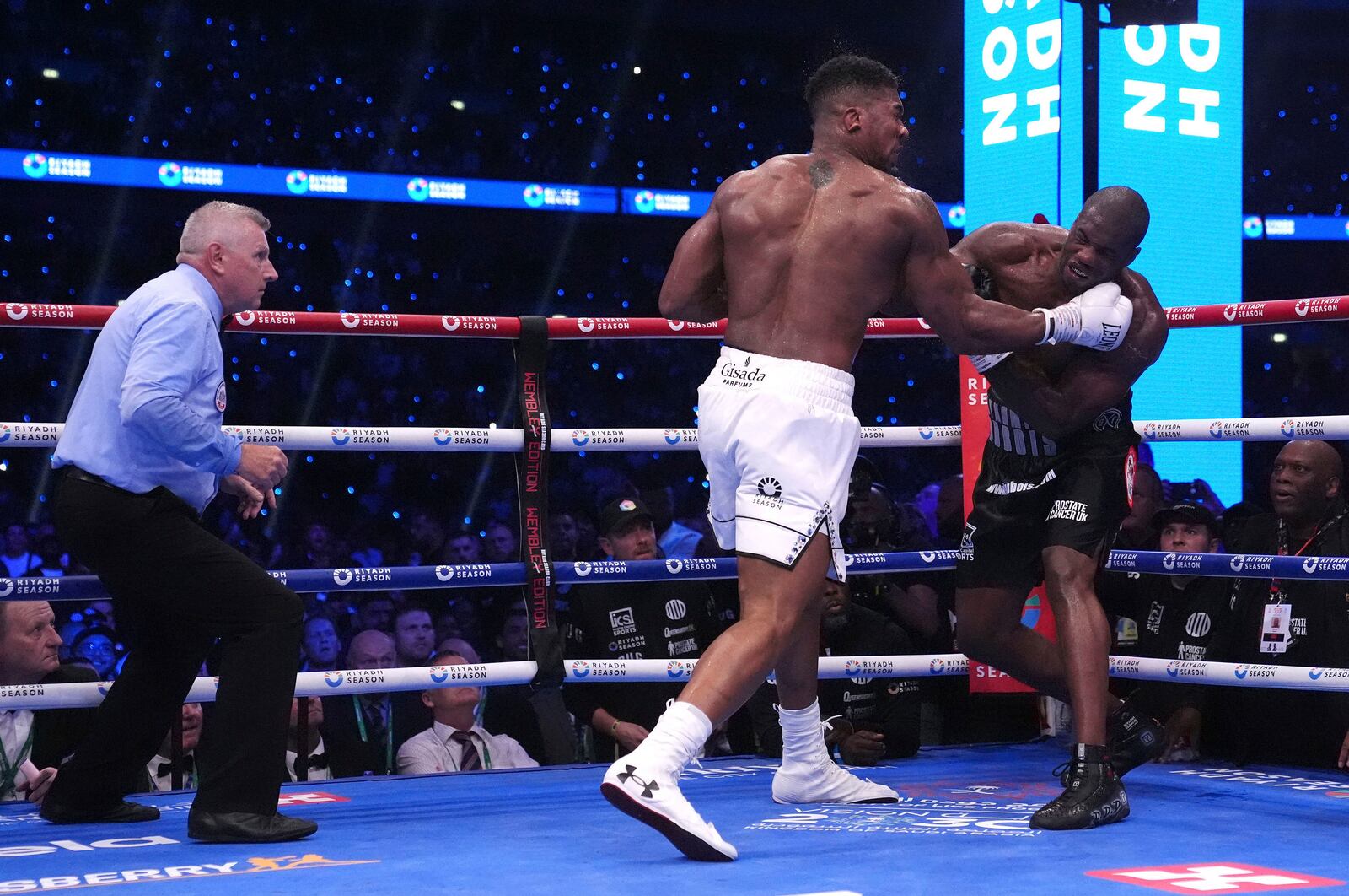 Anthony Joshua, centre, and Daniel Dubois, right, fight in the IBF World Heavyweight bout at Wembley Stadium, in London, Saturday, Sept. 21, 2024. (Bradley Collyer/PA via AP)