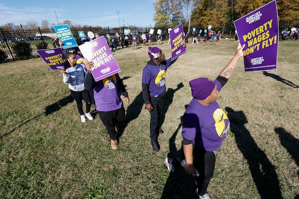 Airport workers wave signs as they march in front of the Charlotte Douglas International Airport in Charlotte, N.C., Monday, Nov. 25, 2024. (AP Photo/Nell Redmond)