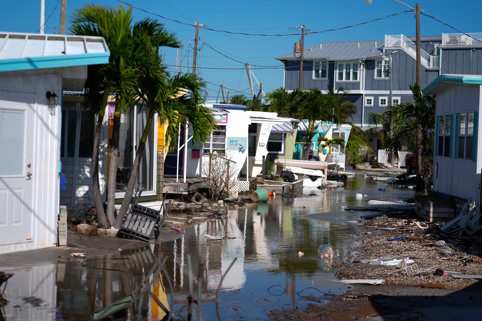 Water left by Hurricane Milton floods a road inside Pines Trailer Park, where debris was still piled outside homes from Hurricane Helene, in Bradenton Beach on Anna Maria Island, Fla., Thursday, Oct. 10, 2024. (AP Photo/Rebecca Blackwell)