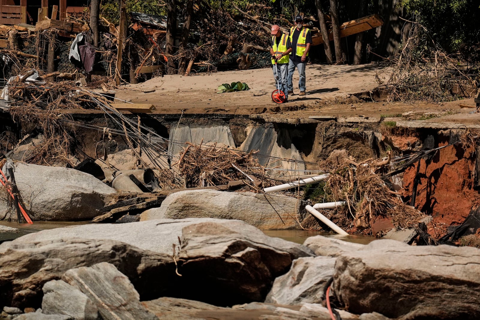 Workers survey damage where a road once existed in the aftermath of Hurricane Helene, Wednesday, Oct. 2, 2024, in Chimney Rock Village, N.C. (AP Photo/Mike Stewart)