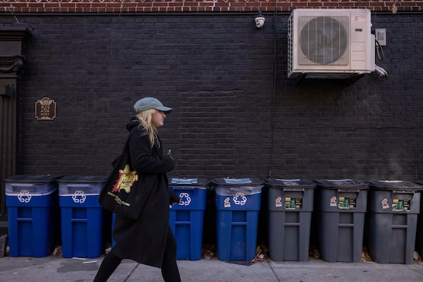 A person walks in front of trash bins, Friday, Nov. 15, 2024, in the Brooklyn borough of New York. (AP Photo/Yuki Iwamura)