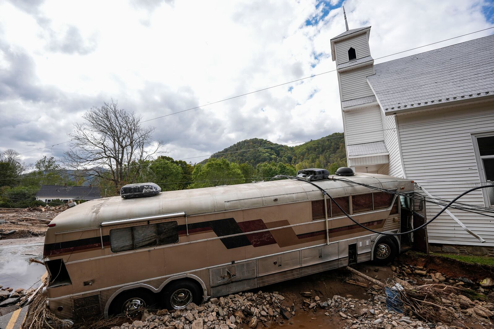 A bus pushed by flood waters rests against Laurel Branch Baptist church in the aftermath of Hurricane Helene, Thursday, Oct. 3, 2024, in Pensacola, N.C. (AP Photo/Mike Stewart)