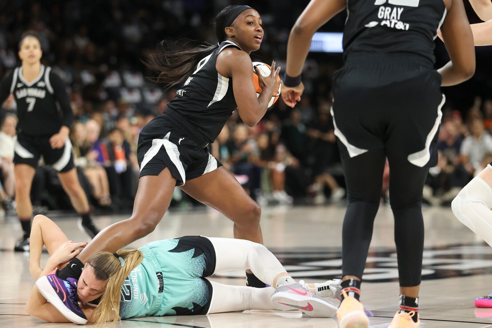 Las Vegas Aces guard Jackie Young (0) attempts to step over New York Liberty guard Sabrina Ionescu (20) during the first half of a WNBA Semifinal game, Sunday, Oct. 6, 2024, in Las Vegas. (AP Photo/Ian Maule)