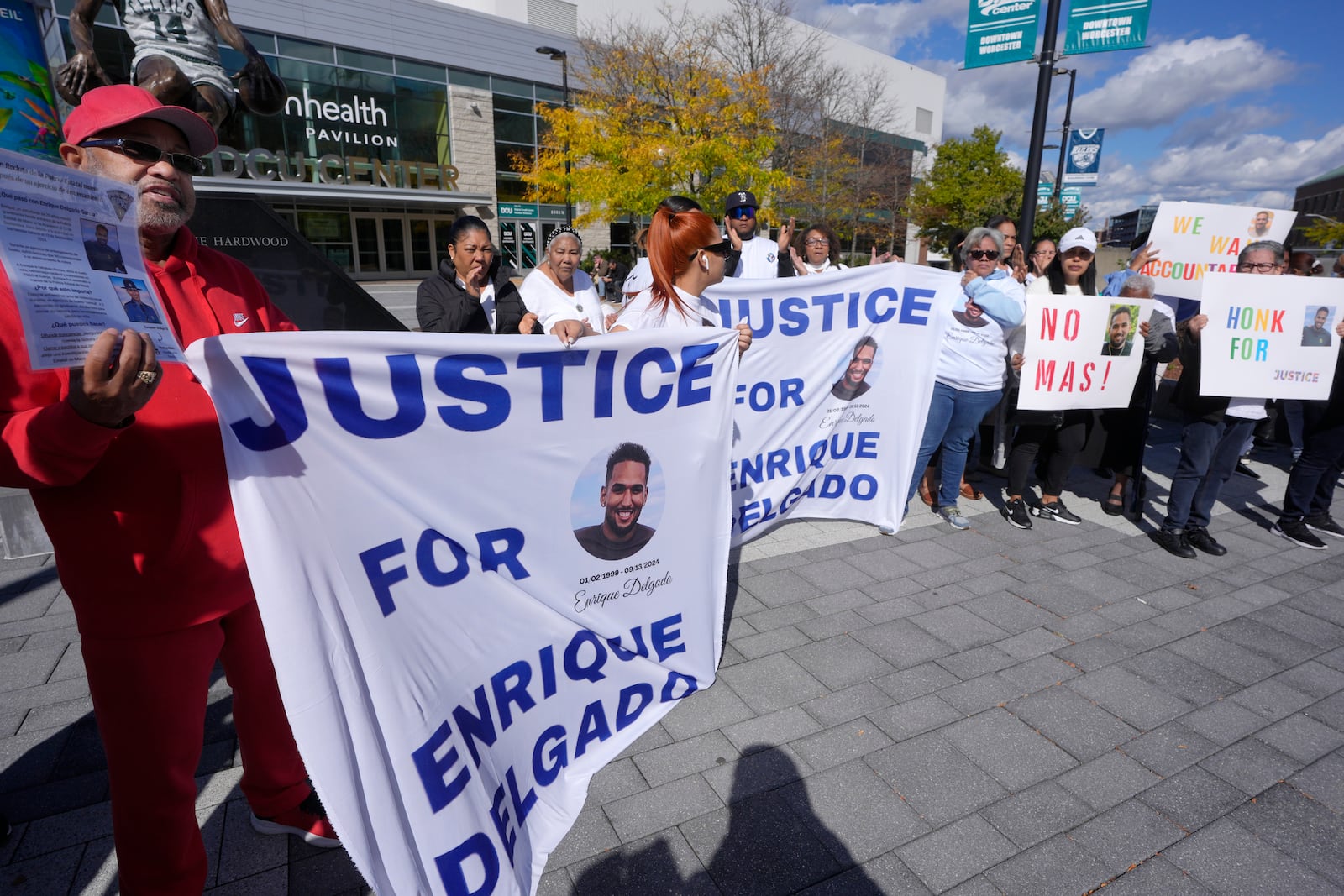 People display signs with with a likeness of Massachusetts State Police recruit Enrique Delgado-Garcia, who died following a State Police Academy training exercise, at a protest outside the State Police Academy graduation ceremony, Wednesday, Oct. 9, 2024, at the DCU Center, in Worcester, Mass. (AP Photo/Steven Senne)