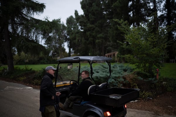 Dean Sweetland, left, talks to a neighbour who works in the Kibbutz Malkiya, northern Israel, Wednesday, Nov. 27, 2024. (AP Photo/Leo Correa)