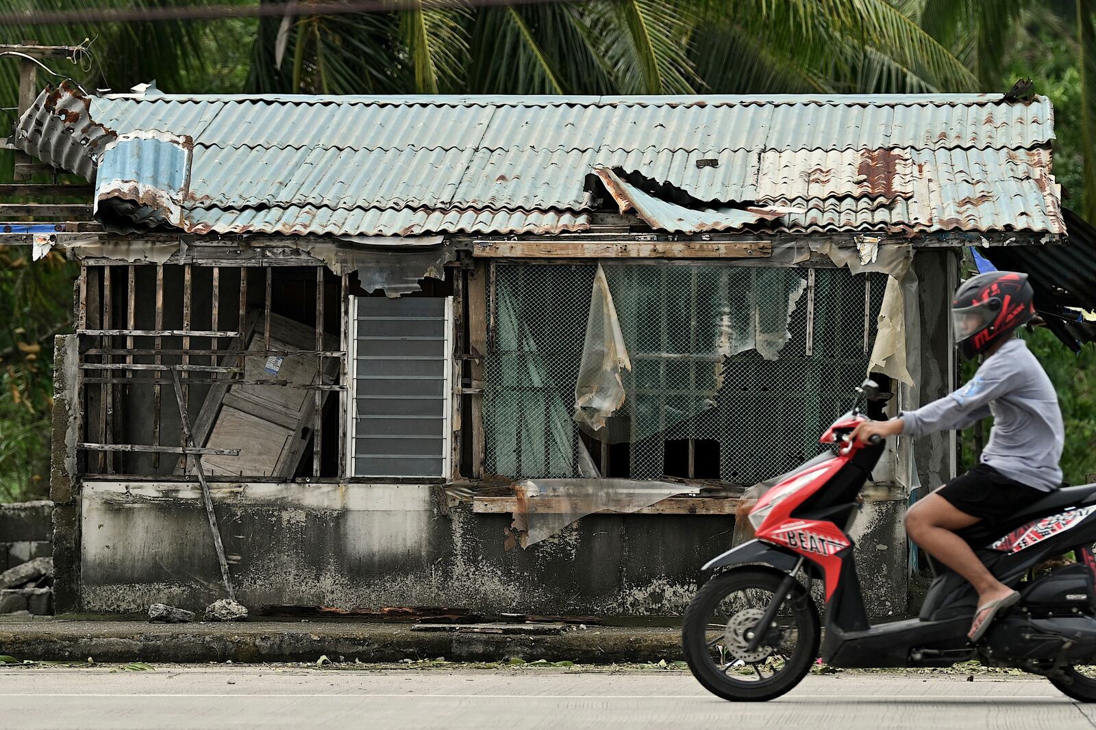 A resident passes by a damaged house after Typhoon Yinxing, locally called Marce, blew past Aparri town, Cagayan province, northern Philippines on Friday, Nov. 8, 2024. (AP Photo/Noel Celis)