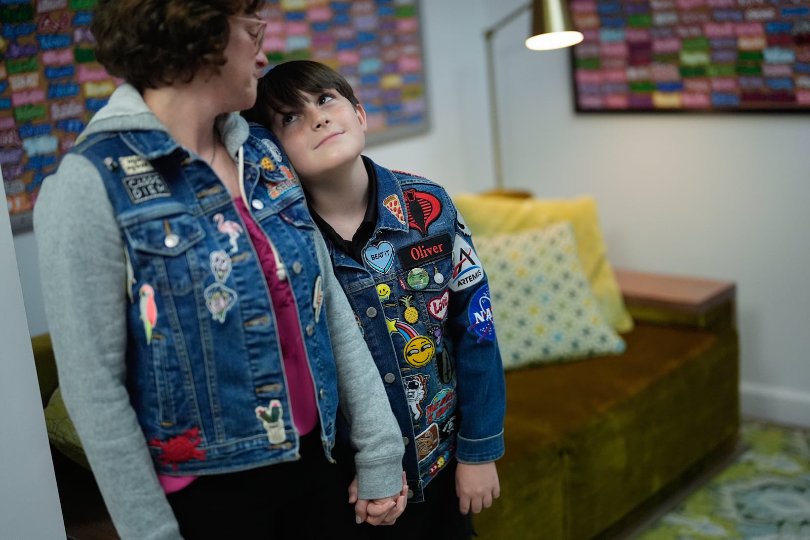 Oliver Burkhardt, 13, looks up at his mom Trisha Brookbank as they hold hands inside the offices of the Oliver Patch Project, Wednesday, Sept. 4, 2024, in Miami. (AP Photo/Rebecca Blackwell)