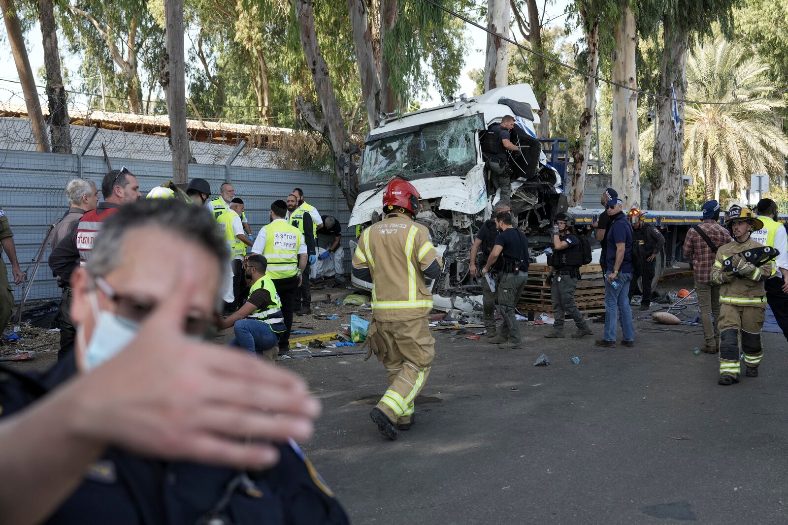 Israeli police and rescue services inspect the body of a truck driver that rammed into a bus stop near the headquarters of Israel's Mossad spy agency, wounding dozens of people, according to Israel's Magen David Adom rescue service in Tel Aviv, Israel, Sunday, Oct. 27, 2024. (AP Photo/Oded Balilty)