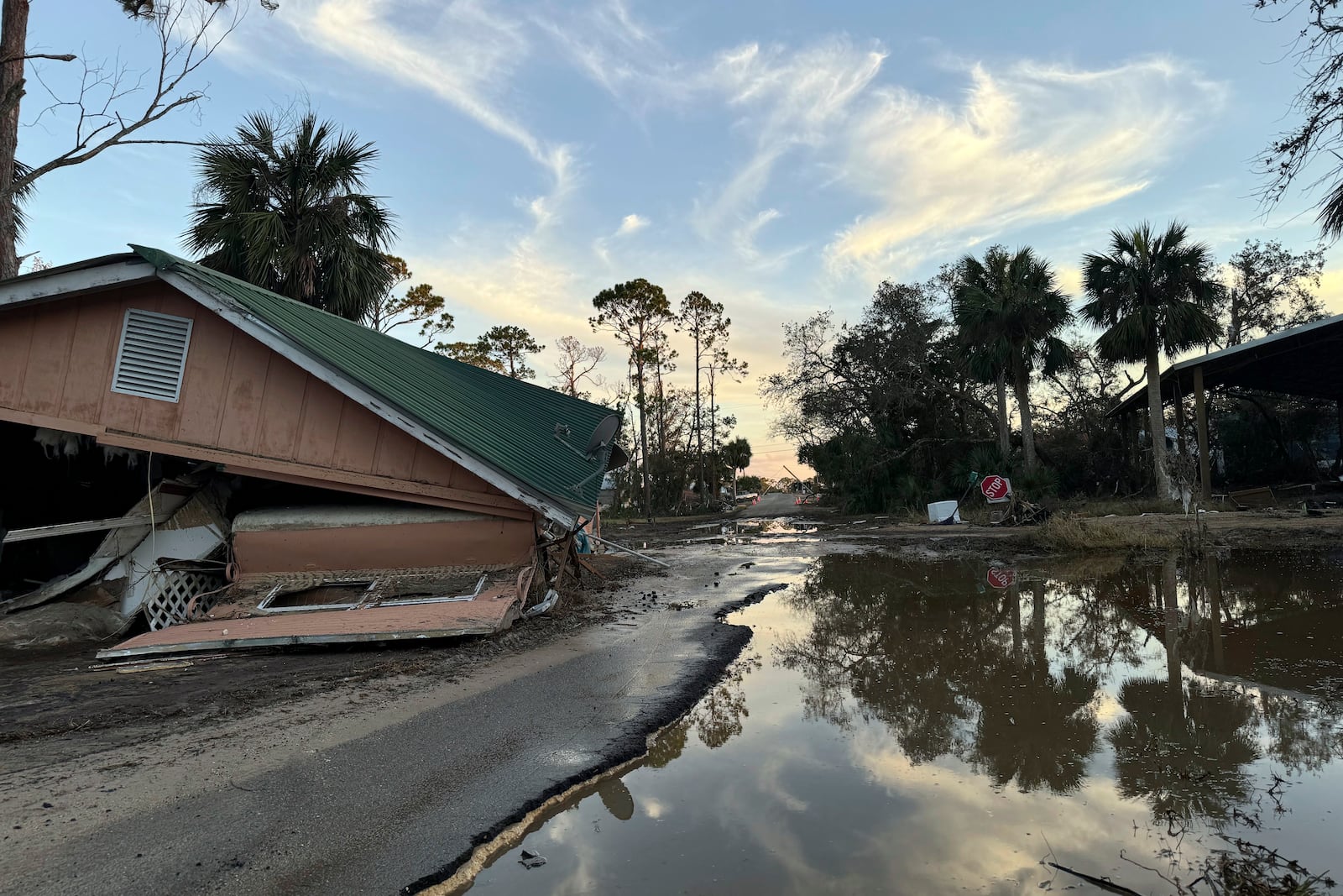 The sun sets over a flooded road and a collapsed building in Steinhatchee, Fla., Sunday, Sept. 29, 2024, in the aftermath of Hurricane Helene. (AP Photo/Kate Payne