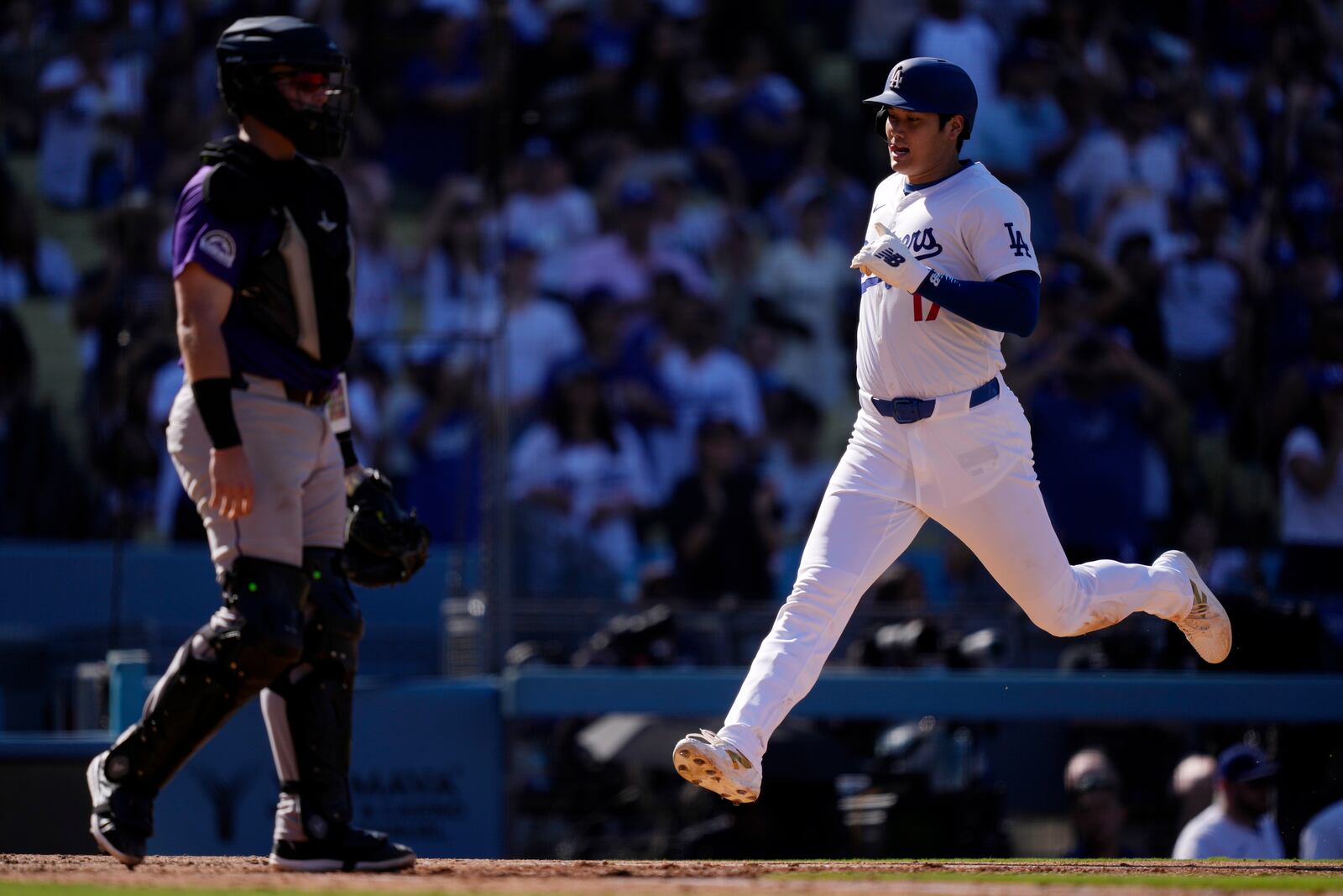 Los Angeles Dodgers' Shohei Ohtani, right, scores on a single by Freddie Freeman as Colorado Rockies catcher Hunter Goodman stands by during the seventh inning of a baseball game against the Colorado Rockies, Sunday, Sept. 22, 2024, in Los Angeles. (AP Photo/Mark J. Terrill)