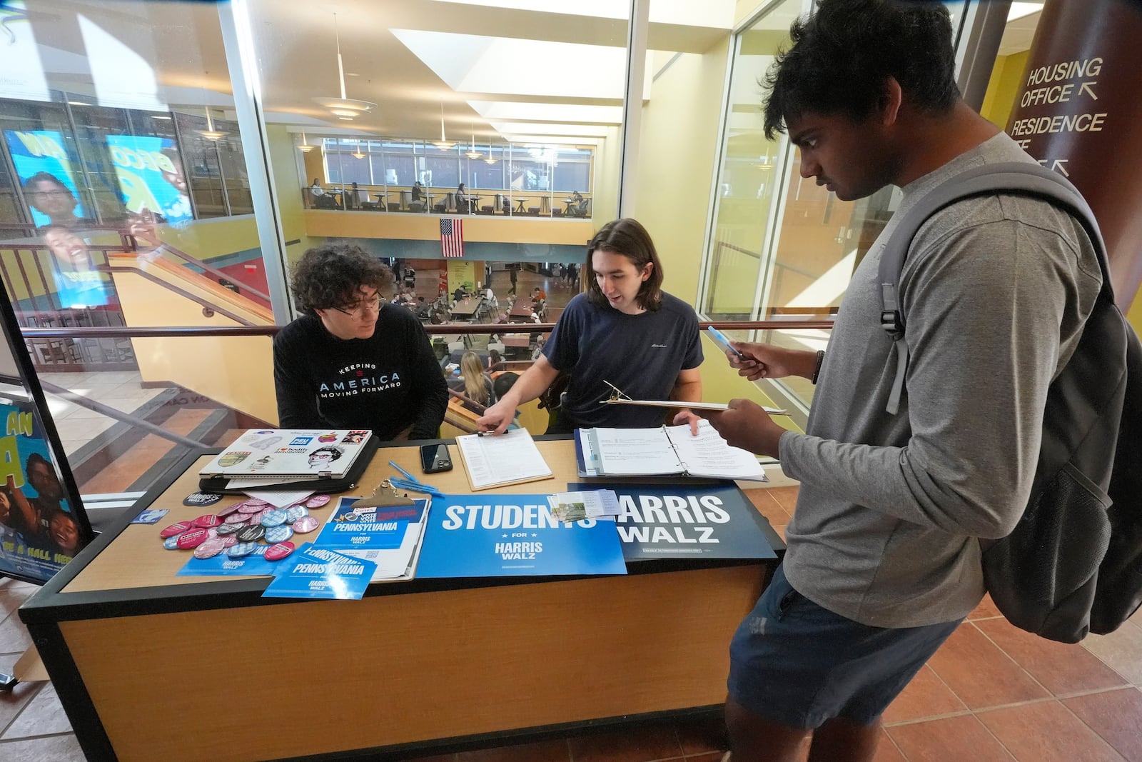 Penn State students Baybars Charkas, left, of Lancaster, Pa., and James Wachtman, center, of Swarthmore, Pa., man a voter registration table on the Penn State campus in University Park, Pa., Friday, Oct. 18, 2024. (AP Photo/Gene J. Puskar)