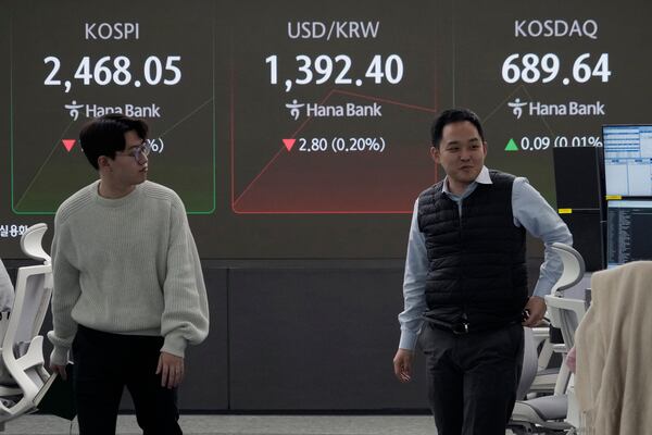 Currency traders pass by a screen showing the Korea Composite Stock Price Index (KOSPI), left, and the foreign exchange rate between U.S. dollar and South Korean won, center, at the foreign exchange dealing room of the KEB Hana Bank headquarters in Seoul, South Korea, Tuesday, Nov. 19, 2024. (AP Photo/Ahn Young-joon)