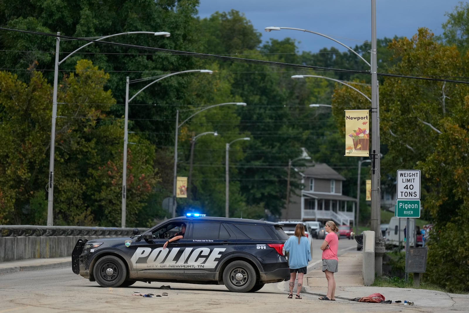 A police car blocks a bridge crossing the Pigeon River in Newport, Tenn., Saturday, Sept. 28, 2024. Tropical depression Helene brought flooding to the area on Friday. (AP Photo/George Walker IV)